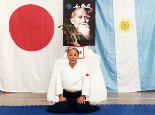 Miyazawa Shihan en seiza, junto a las banderas de Argentina y Japón